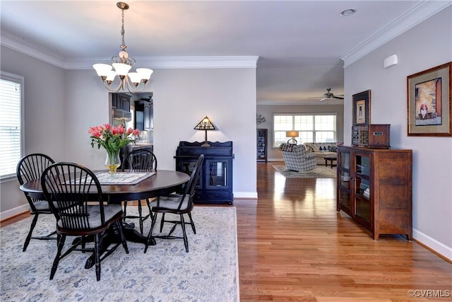 dining room featuring ornamental molding, ceiling fan with notable chandelier, baseboards, and wood finished floors