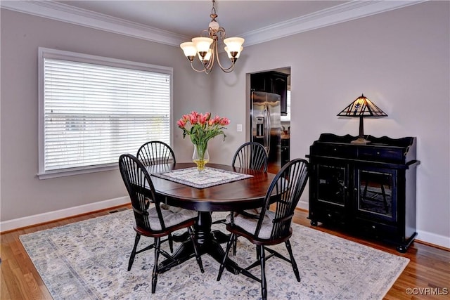 dining area featuring crown molding, baseboards, a notable chandelier, and wood finished floors