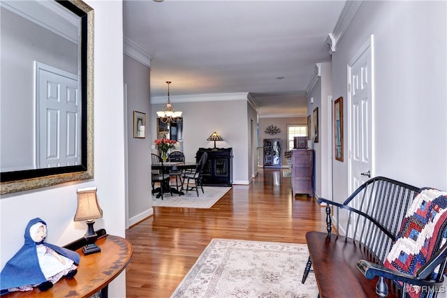 interior space with baseboards, a notable chandelier, ornamental molding, and wood finished floors