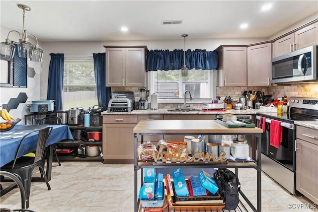 kitchen with tasteful backsplash, visible vents, stainless steel appliances, pendant lighting, and a sink