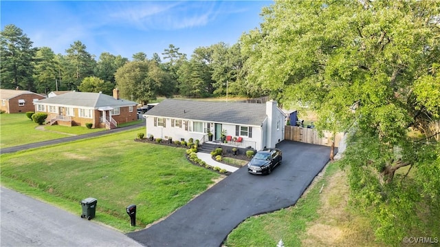 ranch-style house with fence, aphalt driveway, and a front yard