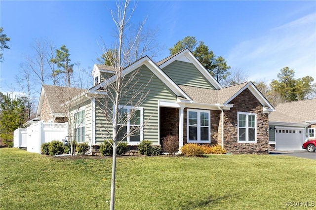 view of front of property featuring stone siding, a front lawn, an attached garage, and fence