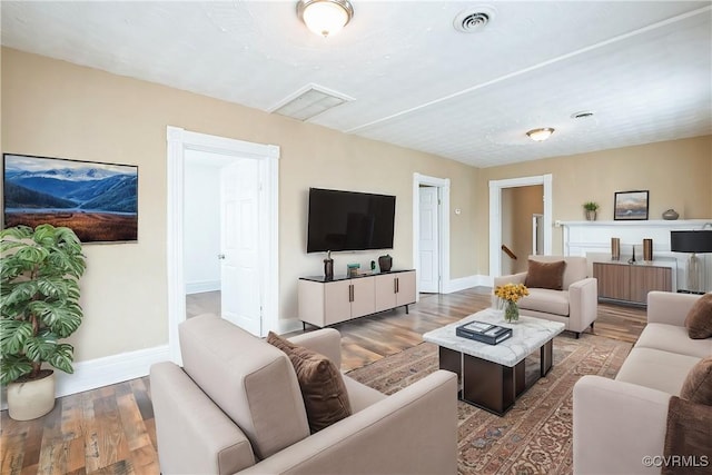 living area with baseboards, wood finished floors, visible vents, and radiator