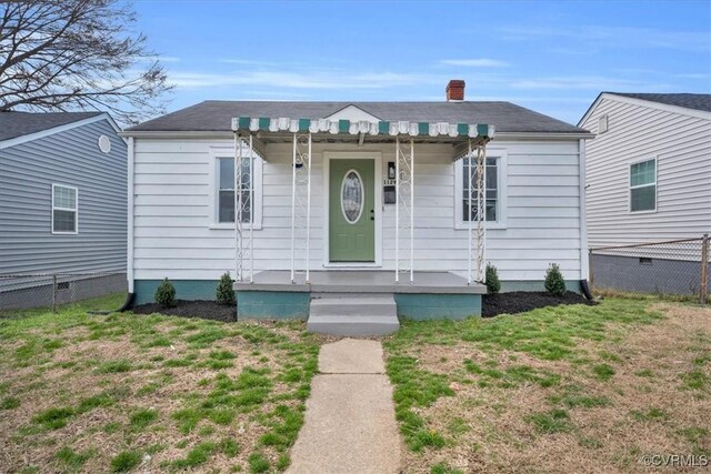 bungalow-style home featuring a chimney, fence, and a front yard