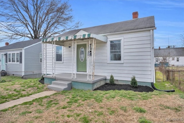 bungalow-style house featuring crawl space, a chimney, fence, and a front yard