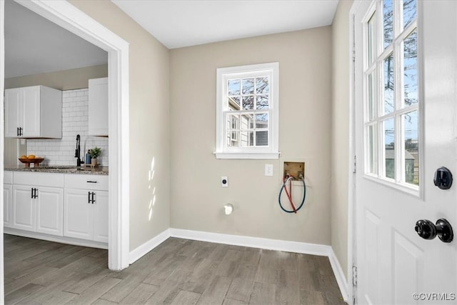 clothes washing area with laundry area, hookup for a washing machine, electric dryer hookup, light wood-type flooring, and a sink