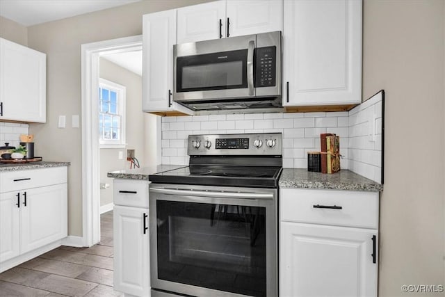 kitchen with stainless steel appliances, white cabinetry, and light stone countertops