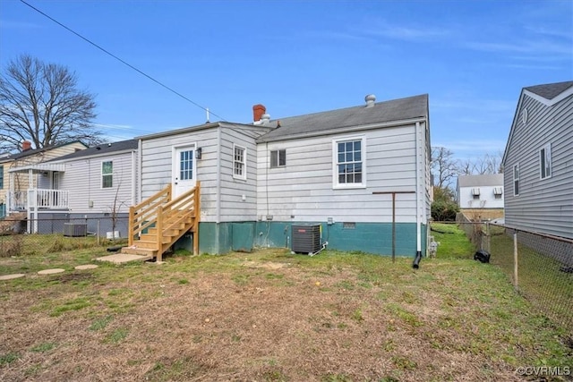 rear view of house with entry steps, central AC unit, a fenced backyard, crawl space, and a yard