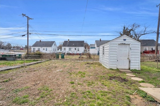 view of yard featuring a storage shed, a residential view, fence, and an outbuilding