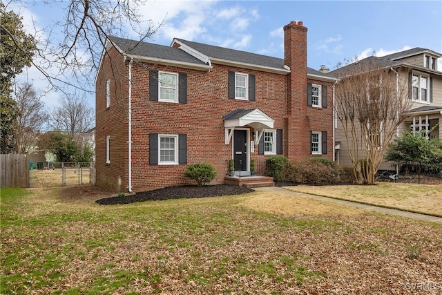 view of front of property featuring a front yard, brick siding, fence, and a chimney