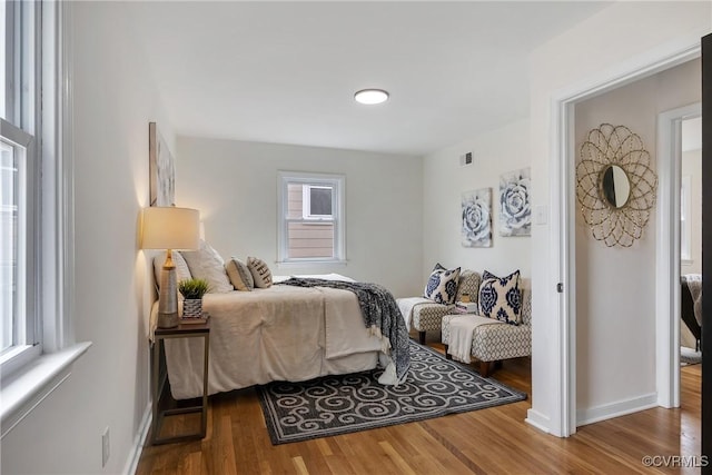 bedroom featuring wood finished floors, visible vents, and baseboards