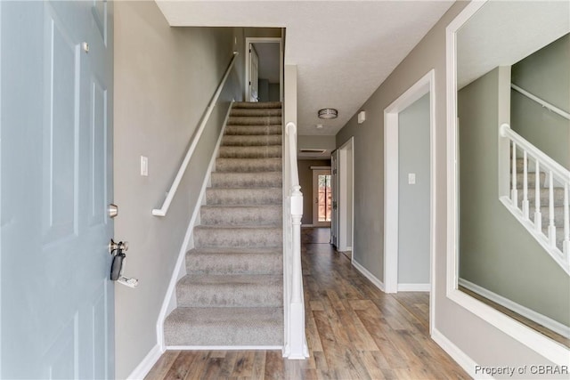 stairs with wood finished floors and baseboards