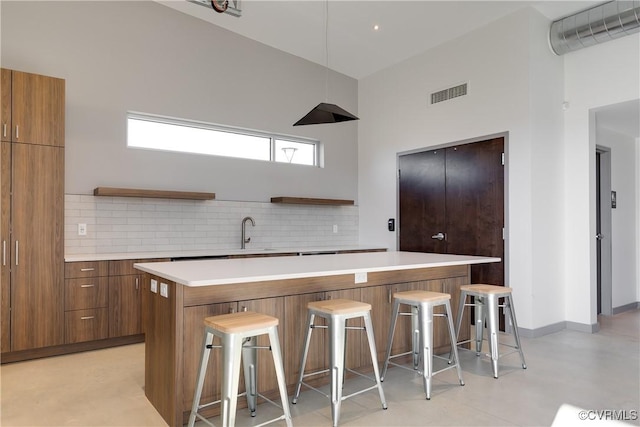 kitchen featuring visible vents, a kitchen breakfast bar, light countertops, open shelves, and brown cabinetry