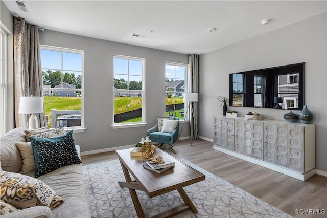 living room featuring light wood-type flooring, visible vents, and plenty of natural light