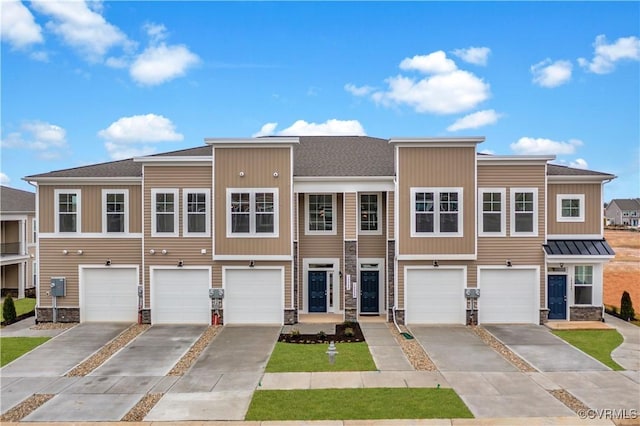 townhome / multi-family property with a garage, stone siding, and concrete driveway