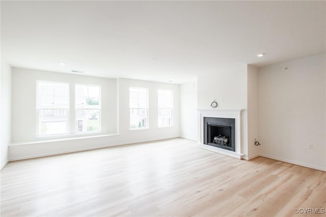 unfurnished living room featuring light wood-style flooring, a fireplace, and baseboards