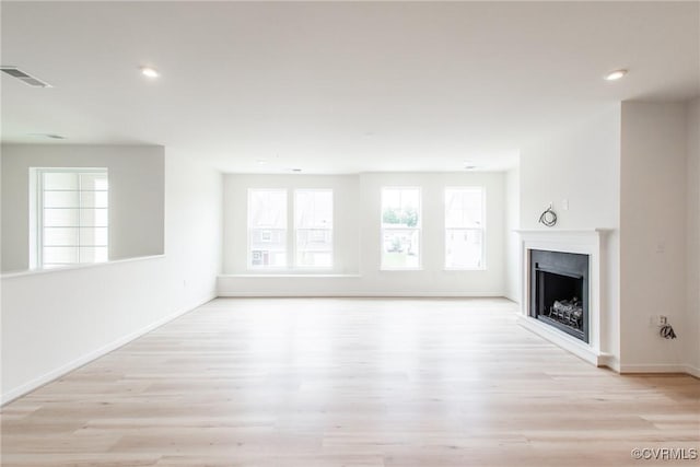 unfurnished living room featuring light wood-type flooring, visible vents, a fireplace, and baseboards