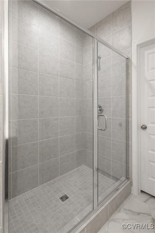 bathroom with marble finish floor and a stall shower