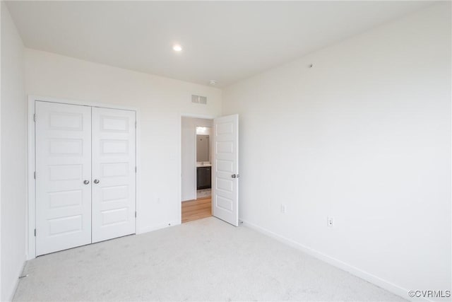 unfurnished bedroom with baseboards, a closet, visible vents, and light colored carpet