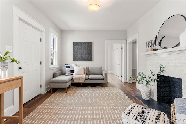 living area featuring a fireplace, baseboards, and wood finished floors