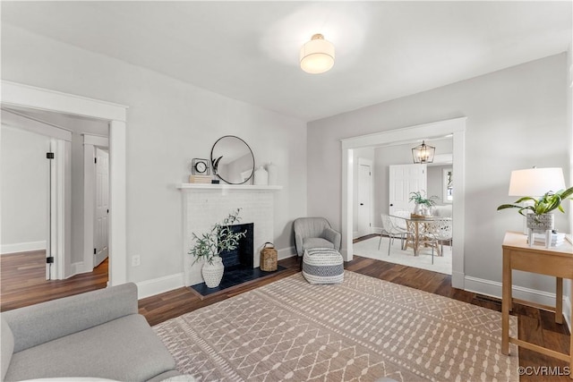 living room featuring a fireplace, baseboards, and wood finished floors