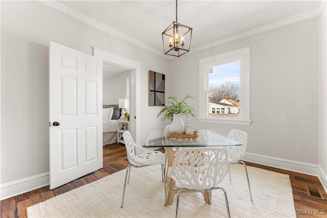 dining room featuring crown molding, visible vents, wood finished floors, a chandelier, and baseboards