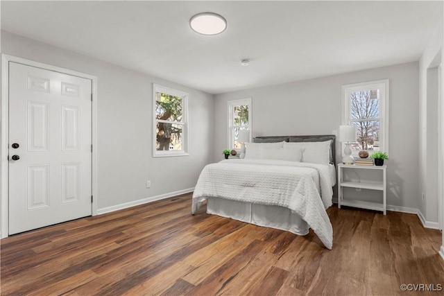 bedroom featuring multiple windows, baseboards, and wood finished floors