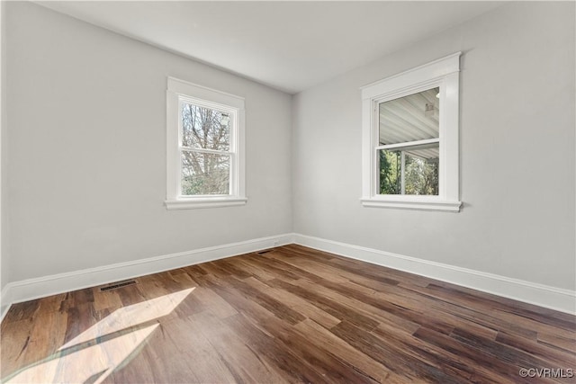 empty room with a healthy amount of sunlight, baseboards, and wood finished floors