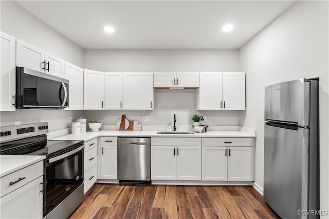 kitchen featuring stainless steel appliances, dark wood-style flooring, a sink, white cabinetry, and light countertops