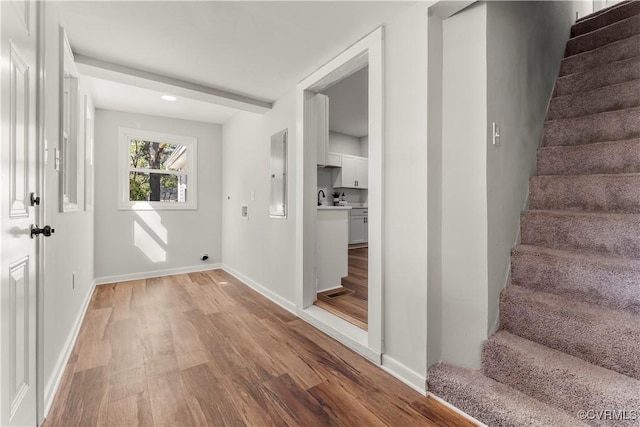 interior space featuring electric panel, baseboards, stairway, light wood-type flooring, and a sink