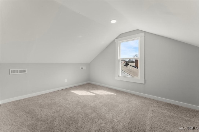 additional living space with vaulted ceiling, carpet floors, visible vents, and baseboards