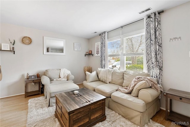 living room featuring visible vents, baseboards, and wood finished floors