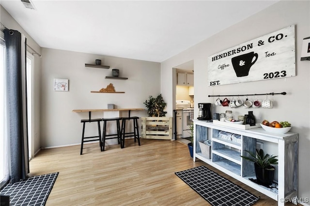 interior space with baseboards, white range with electric stovetop, visible vents, and wood finished floors