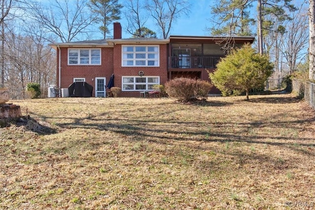 back of house with brick siding, a yard, a chimney, and fence