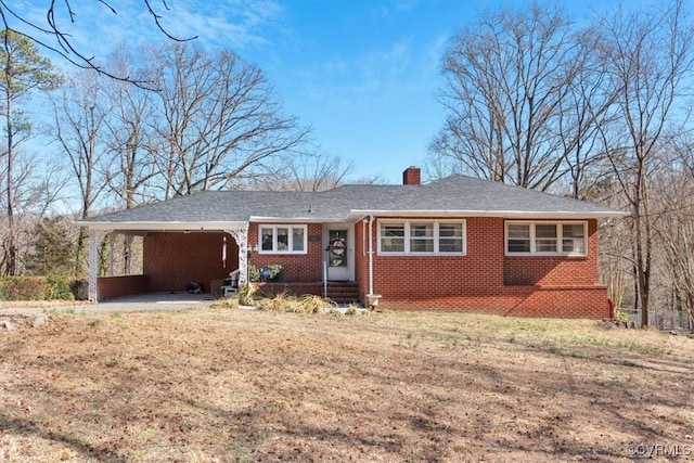 ranch-style home featuring a chimney, a front lawn, a carport, and brick siding