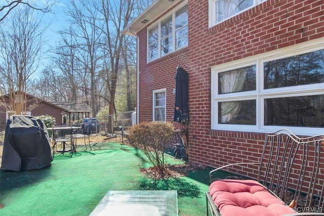 exterior space with brick siding, fence, and a lawn