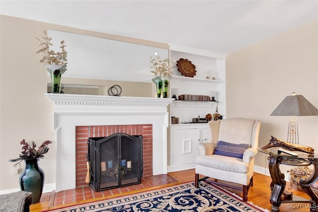 sitting room featuring a brick fireplace and baseboards