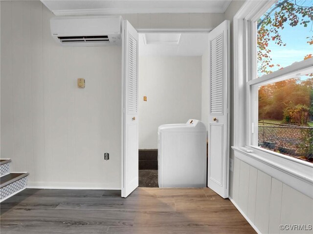 laundry room with washer / clothes dryer, a wealth of natural light, wood finished floors, and a wall mounted AC