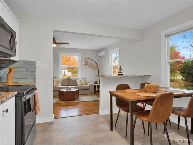 dining area featuring baseboards, a ceiling fan, and a wall mounted air conditioner