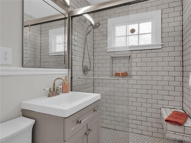 full bathroom with toilet, tiled shower, and vanity