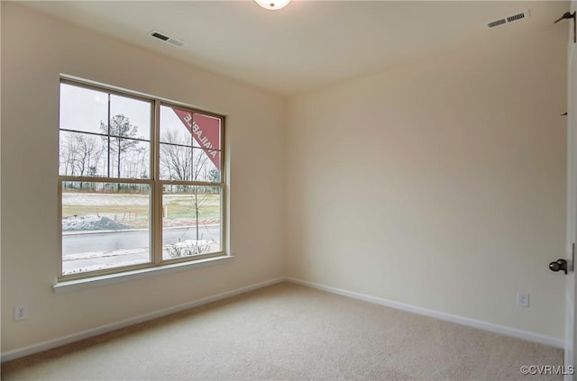 spare room featuring light colored carpet, visible vents, and baseboards