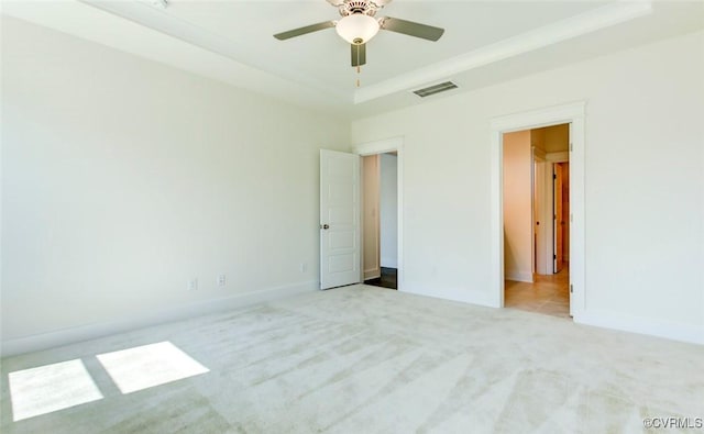 unfurnished bedroom with carpet floors, a raised ceiling, visible vents, and baseboards