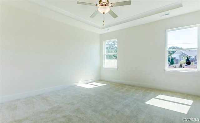 unfurnished room with visible vents, baseboards, a ceiling fan, a tray ceiling, and carpet floors