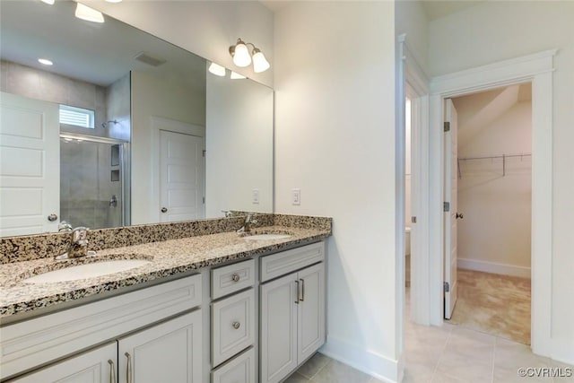 bathroom featuring a stall shower, tile patterned floors, a sink, and double vanity