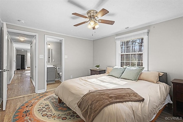 bedroom featuring baseboards, a textured ceiling, wood finished floors, and ornamental molding