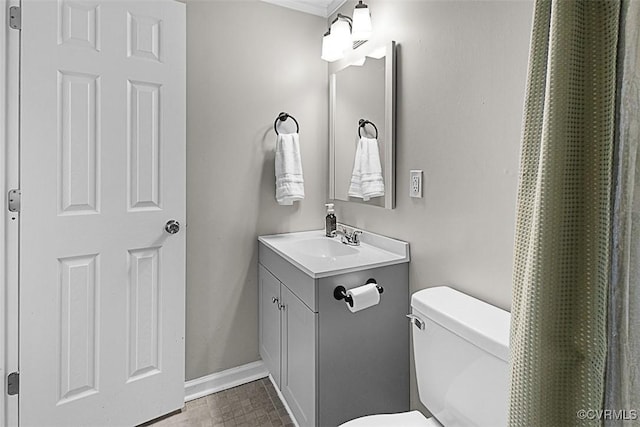 bathroom with toilet, vanity, and baseboards