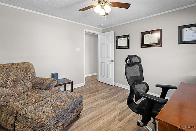 office featuring baseboards, light wood finished floors, ceiling fan, a textured ceiling, and crown molding