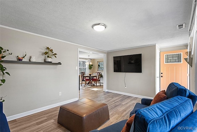 living area featuring a textured ceiling, crown molding, baseboards, and wood finished floors