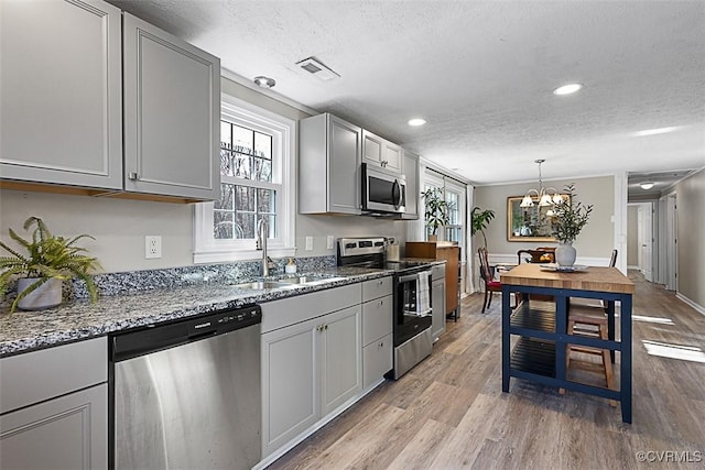 kitchen featuring light wood finished floors, visible vents, appliances with stainless steel finishes, a textured ceiling, and a sink