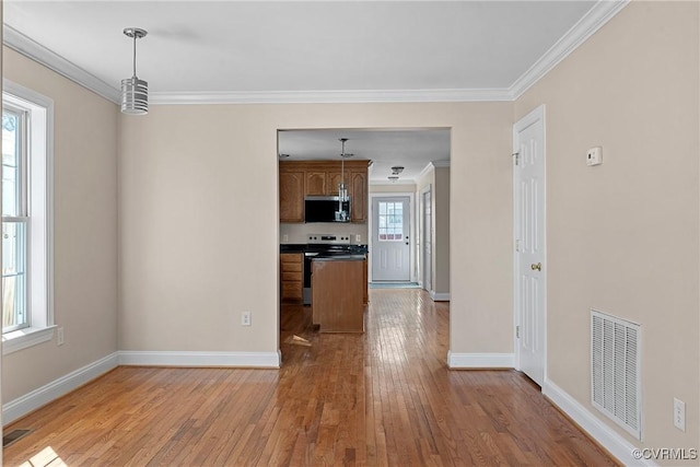 kitchen with ornamental molding, appliances with stainless steel finishes, hardwood / wood-style flooring, and visible vents